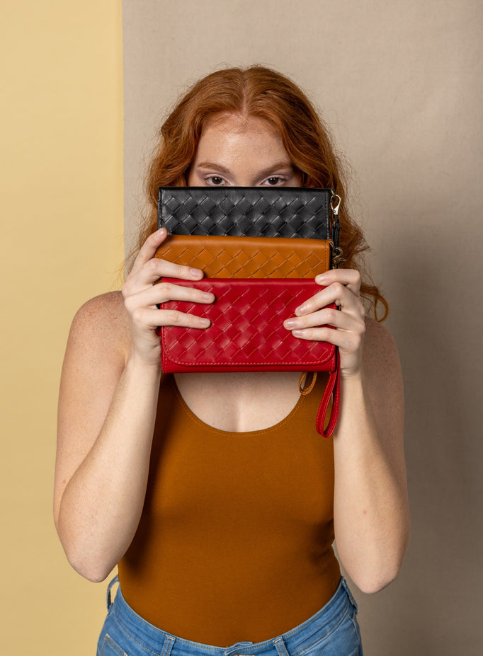 model sitting and leaning on a box holding the woven wristlets in sky blue and sage green.